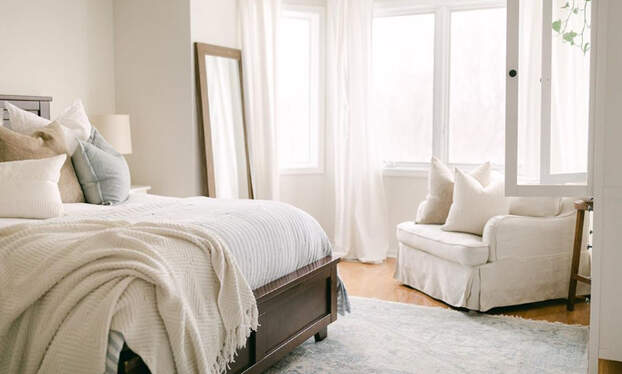 neutral bedroom with mirror and chair