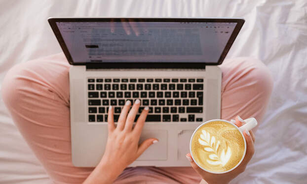 The Hm Blog, woman holding a cup of coffee with a laptop