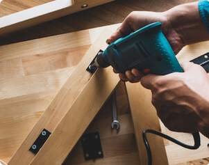 man using electric drill on furniture