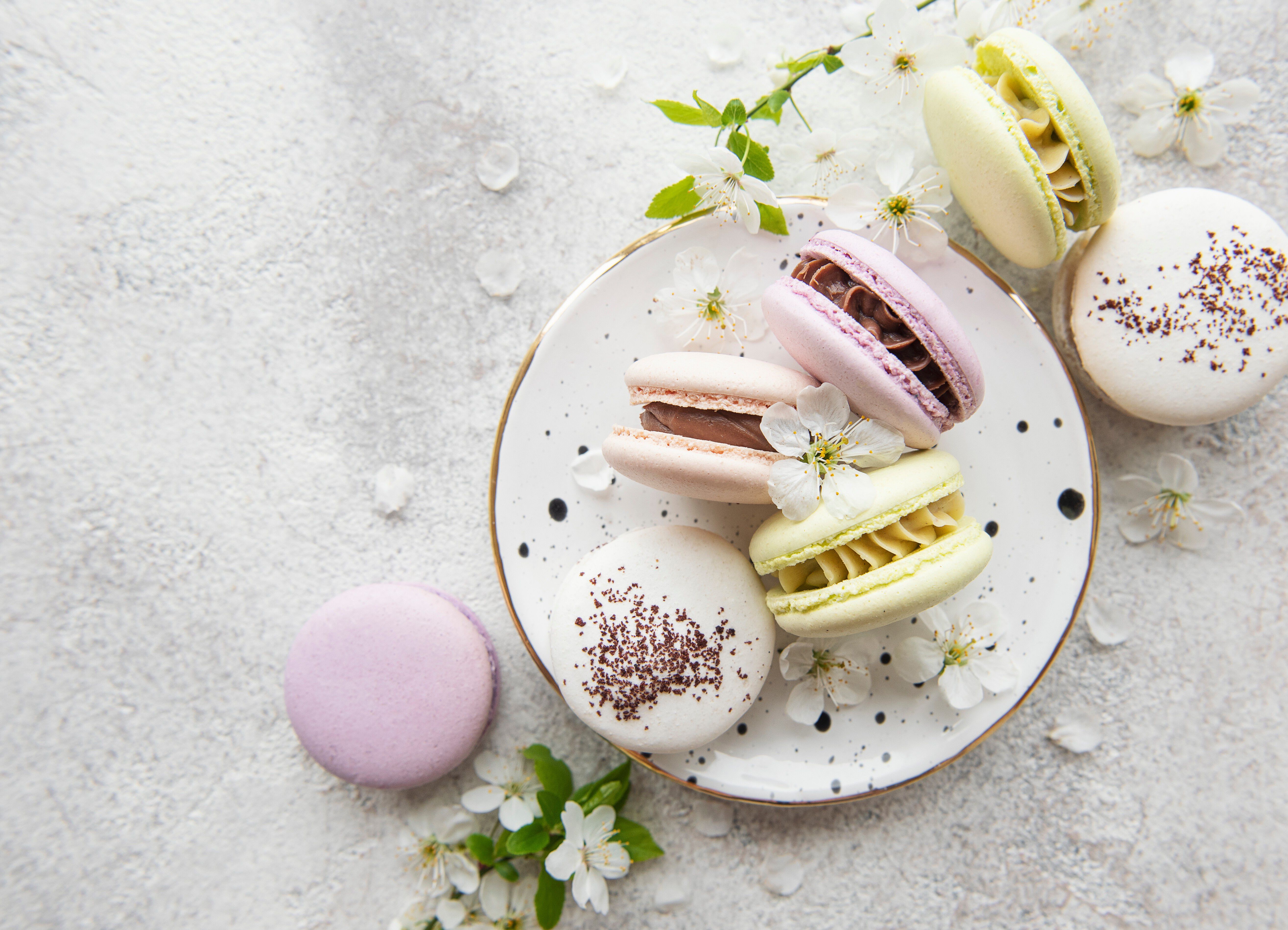 Pastel macrons on gold rim white plate and small white petal flowers