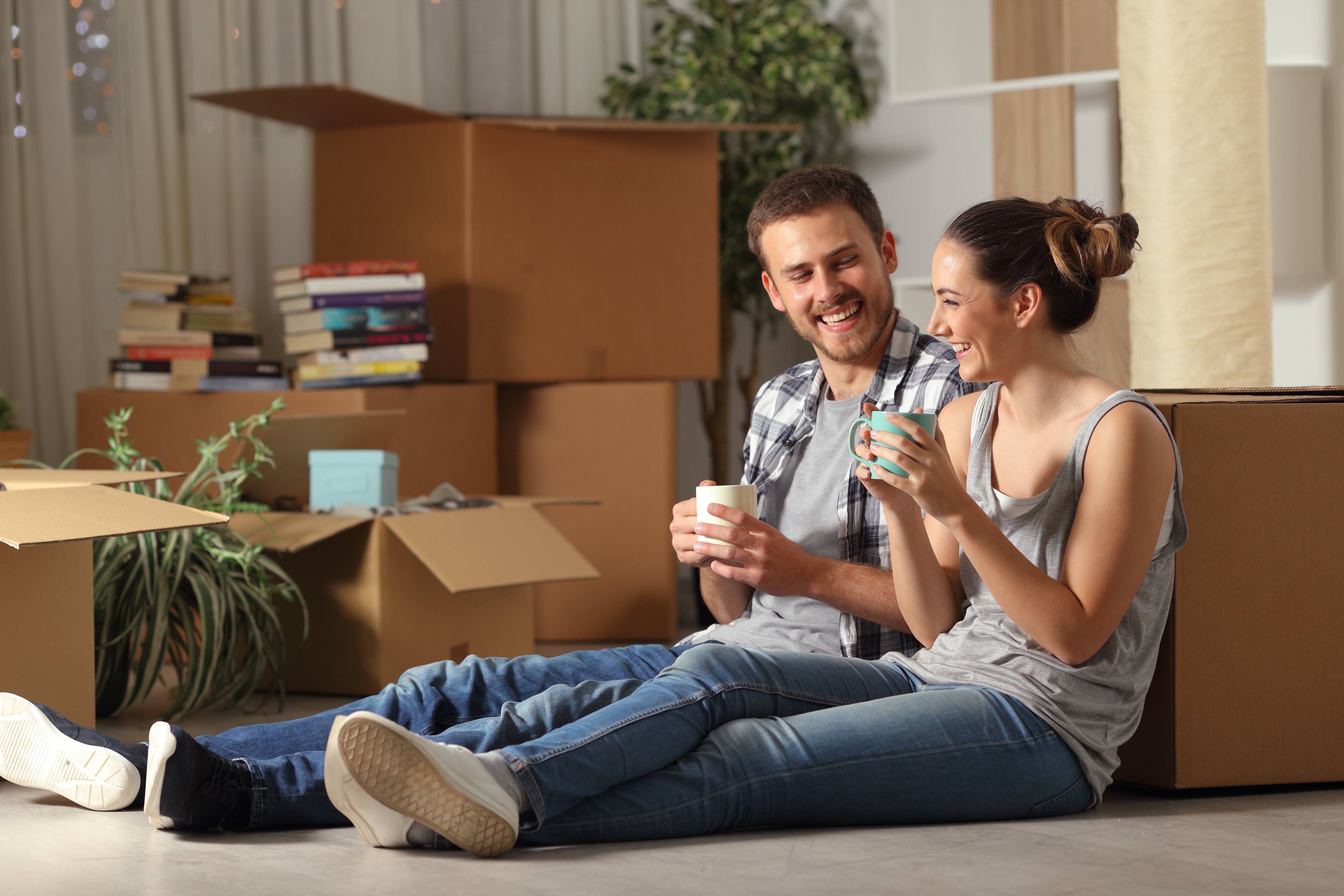 Couple sitting on floor surrounded by moving boxes