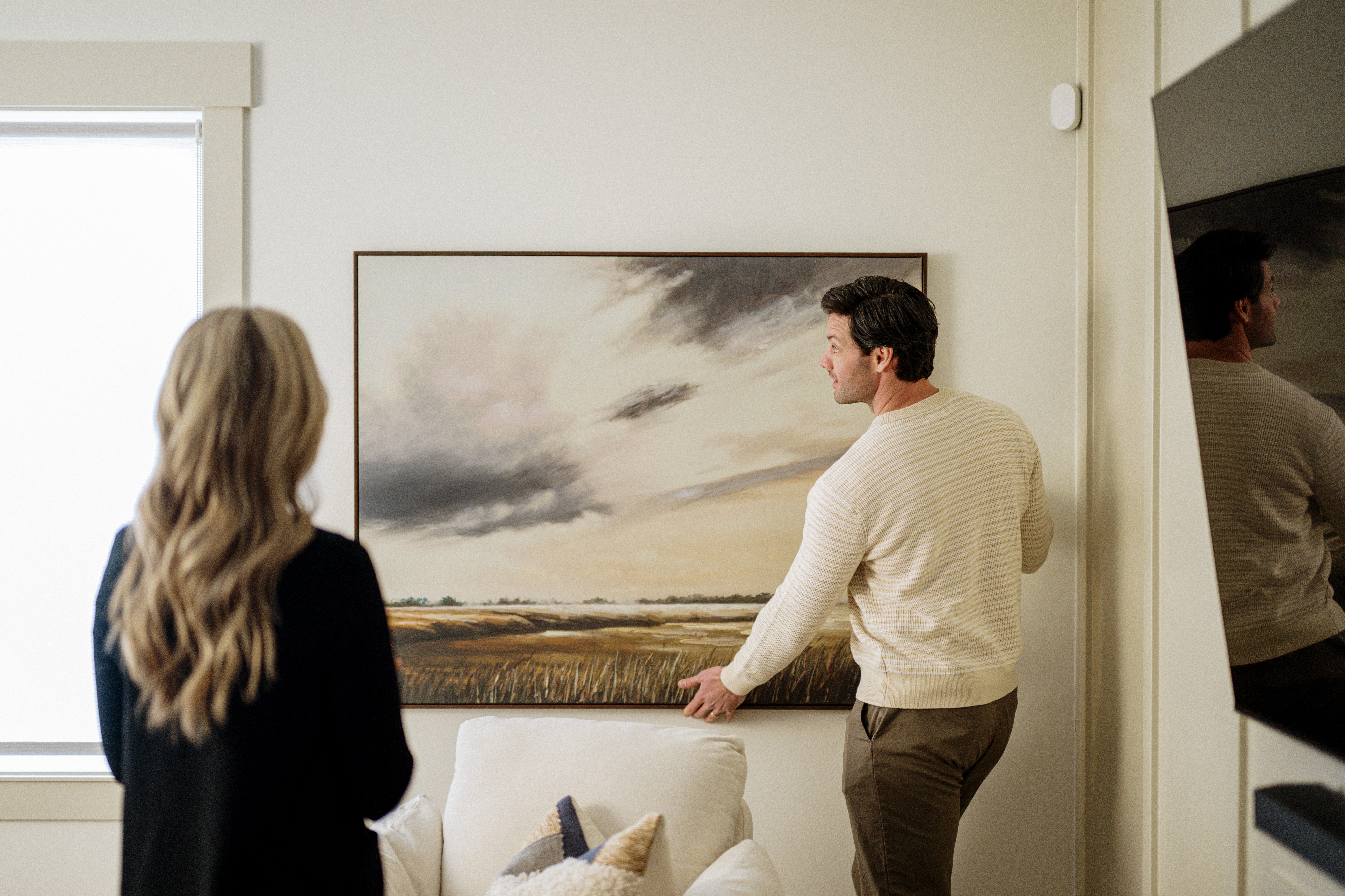 A young couple hanging a piece of art up in new place