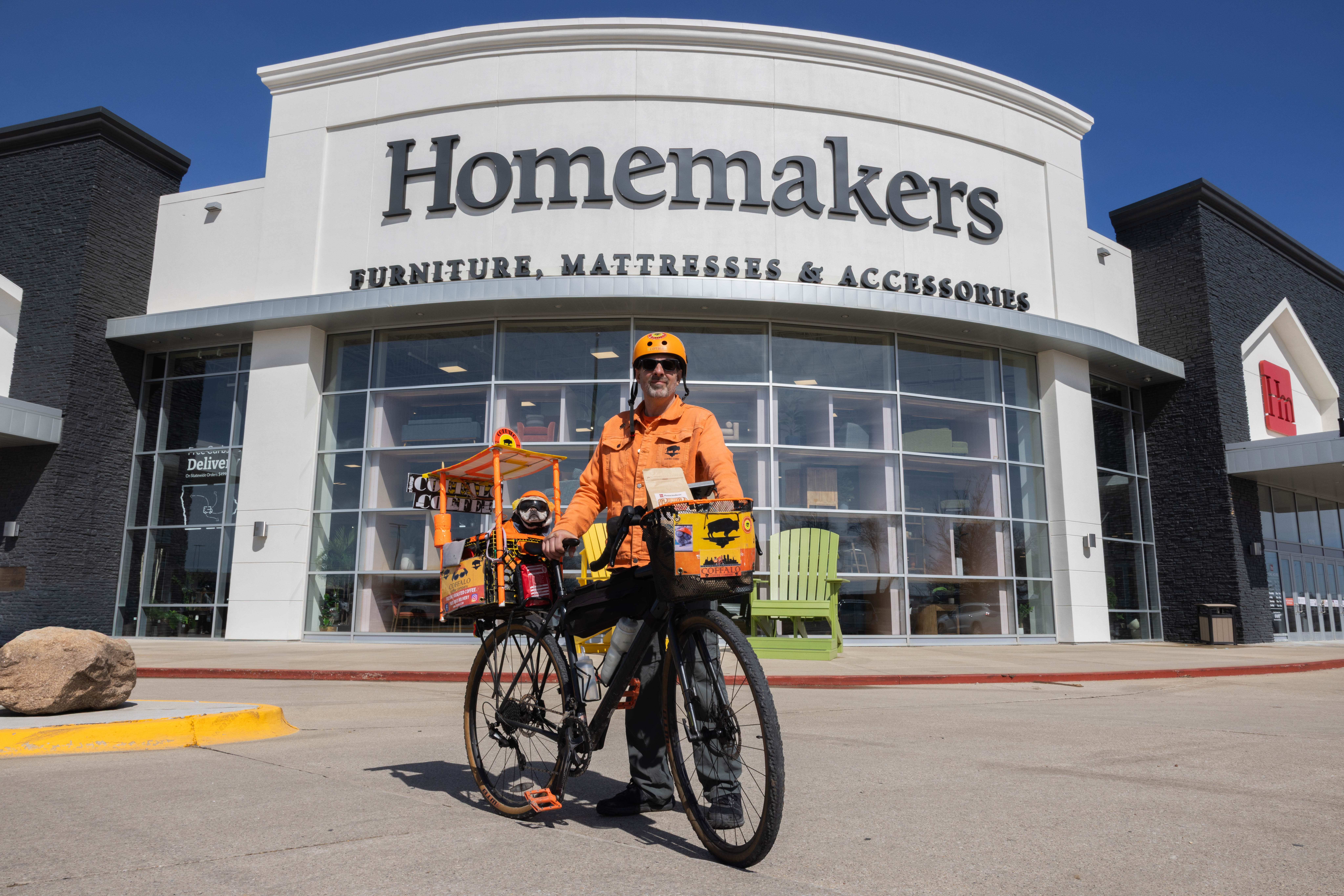 Chris James' on bike in front of Homemakers Furniture Showroom
