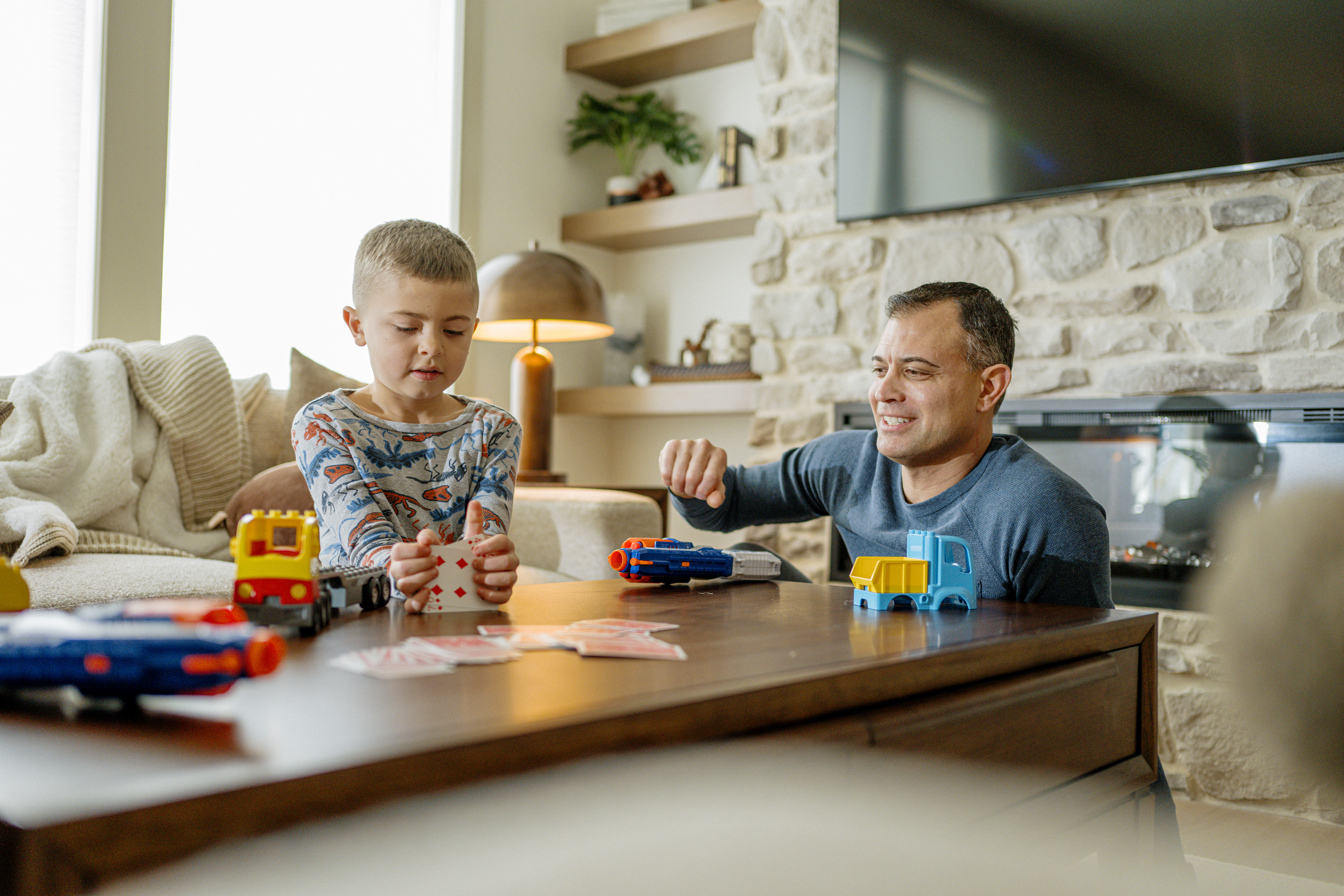 Dad and son playing with toys and cards in living room