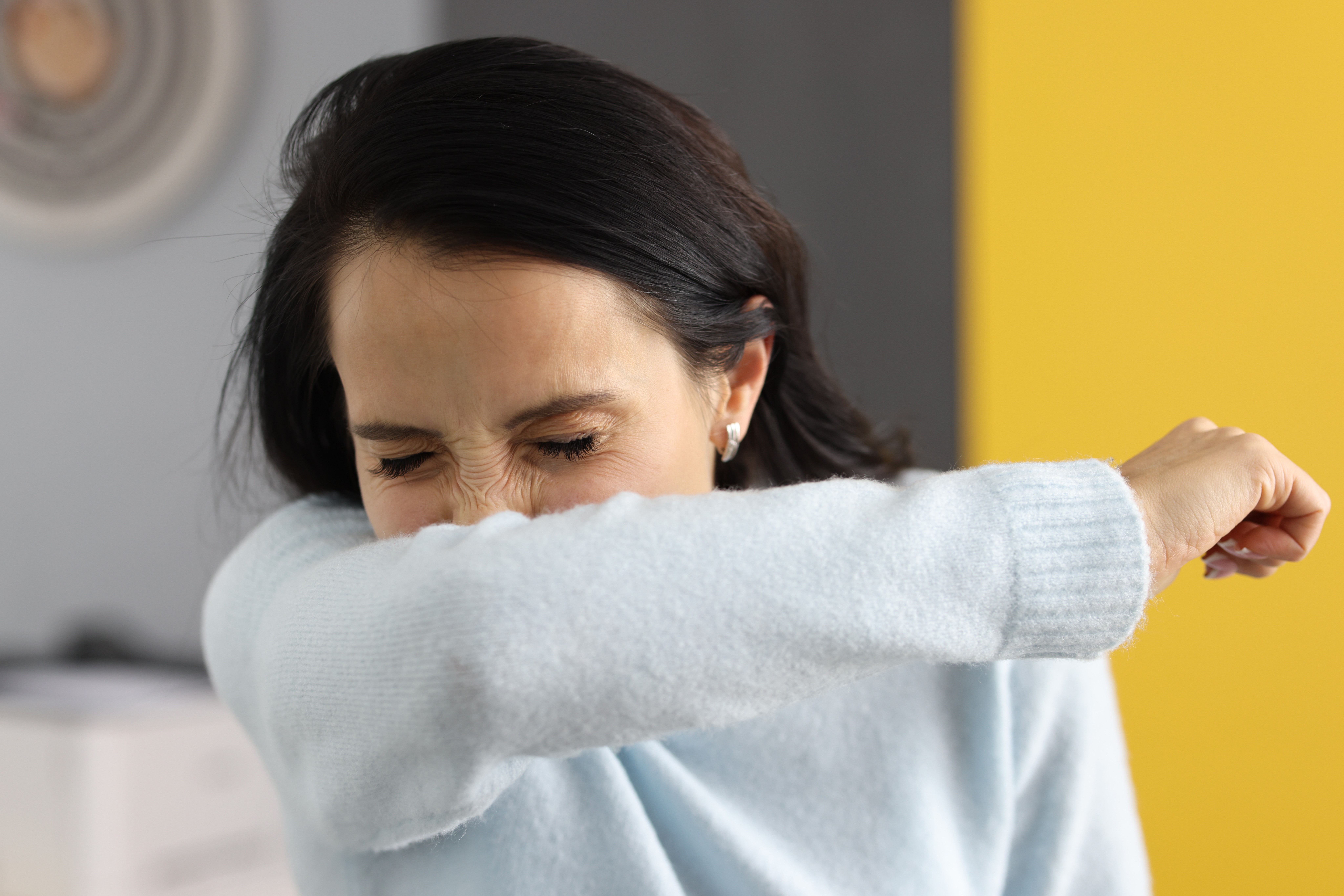 Woman sneezing into her elbow