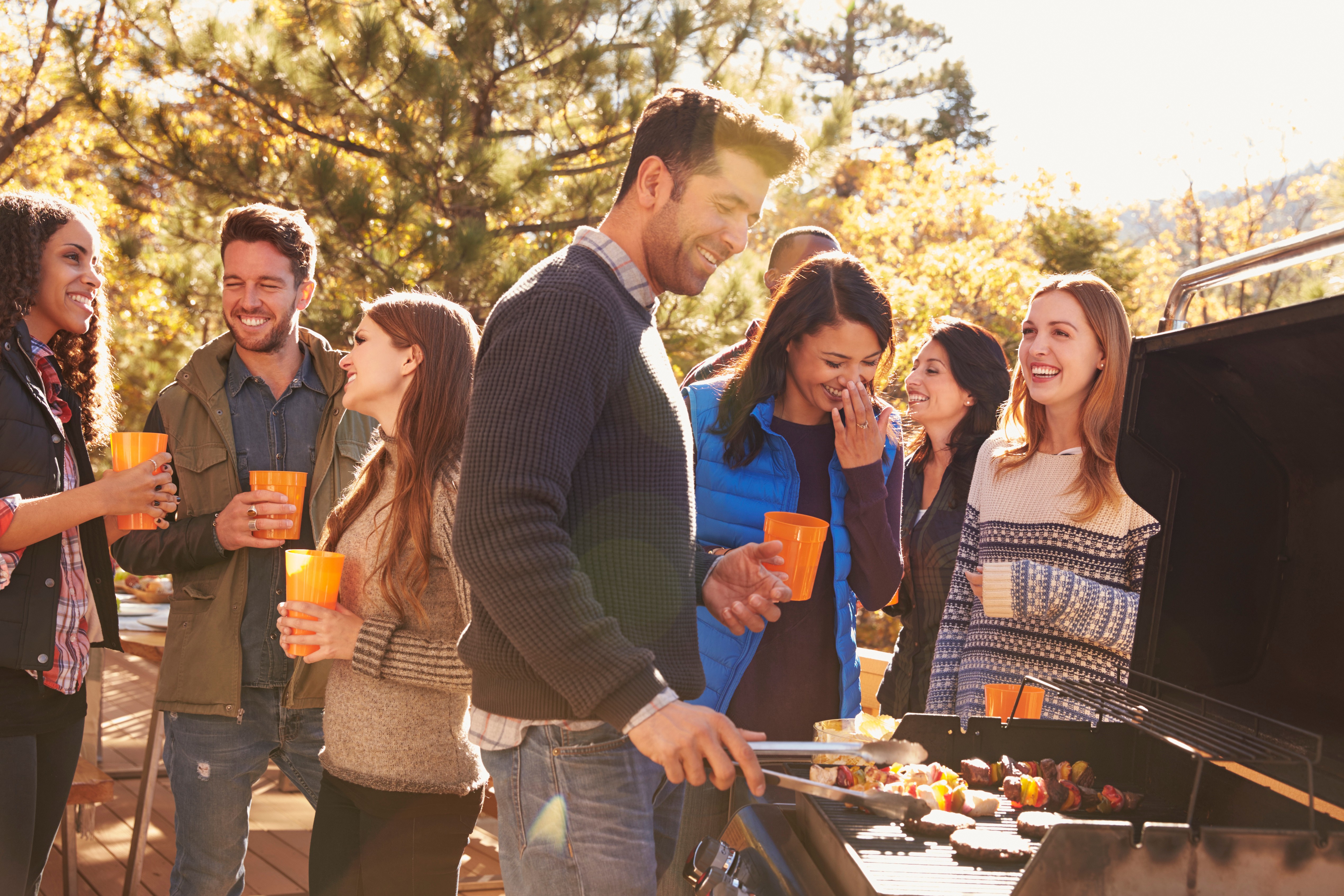 friends hanging out by the grill in autumn