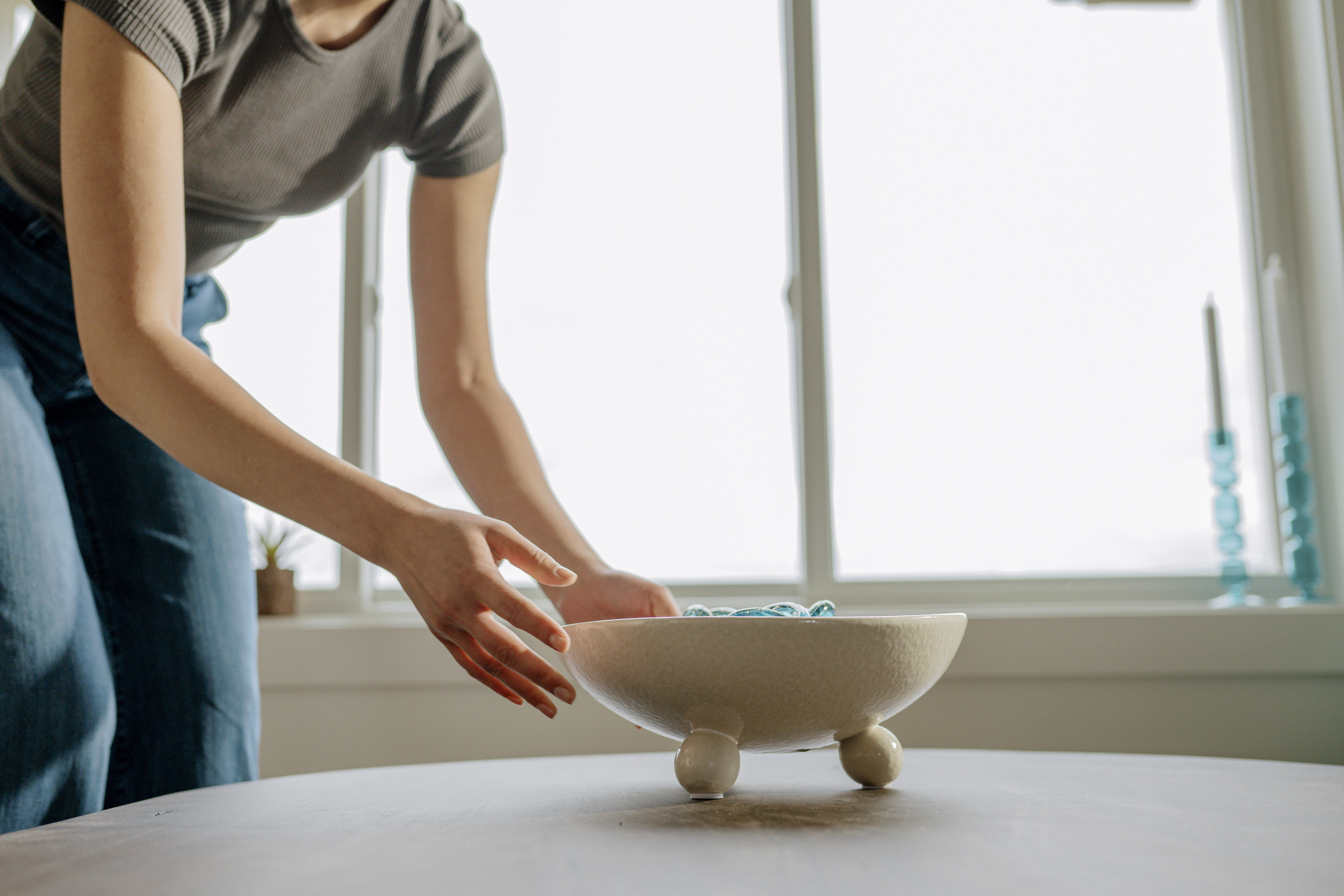 Hands adding a decorative bowl to a bare coffee table