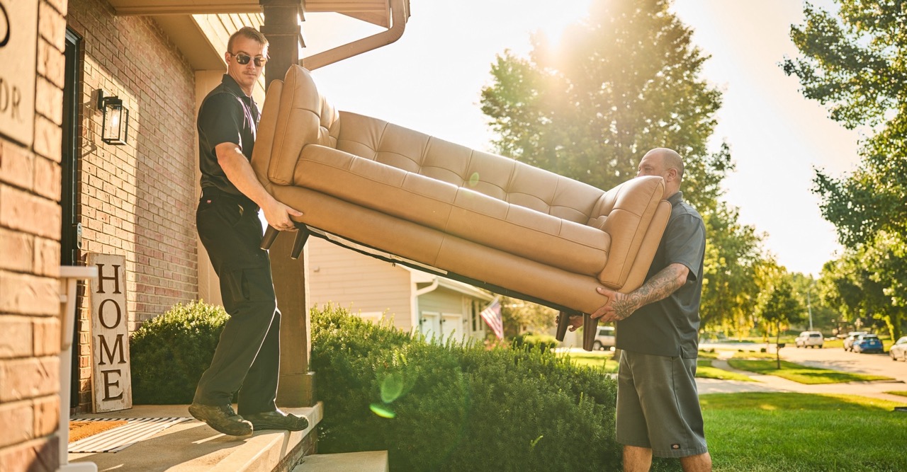 two in-home delivery team members carrying a furniture inside a home