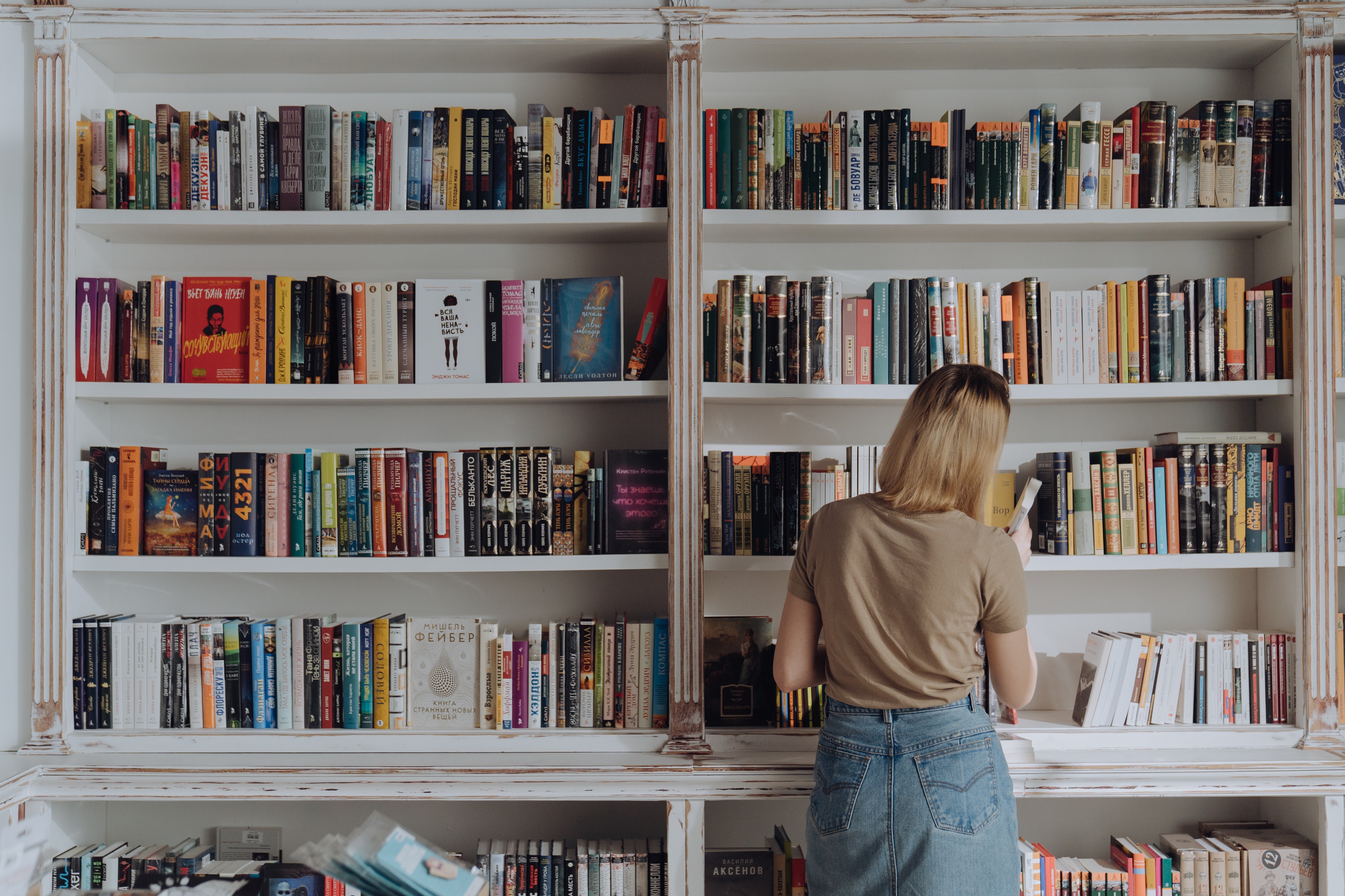 Girl searching for books on a bookshelf