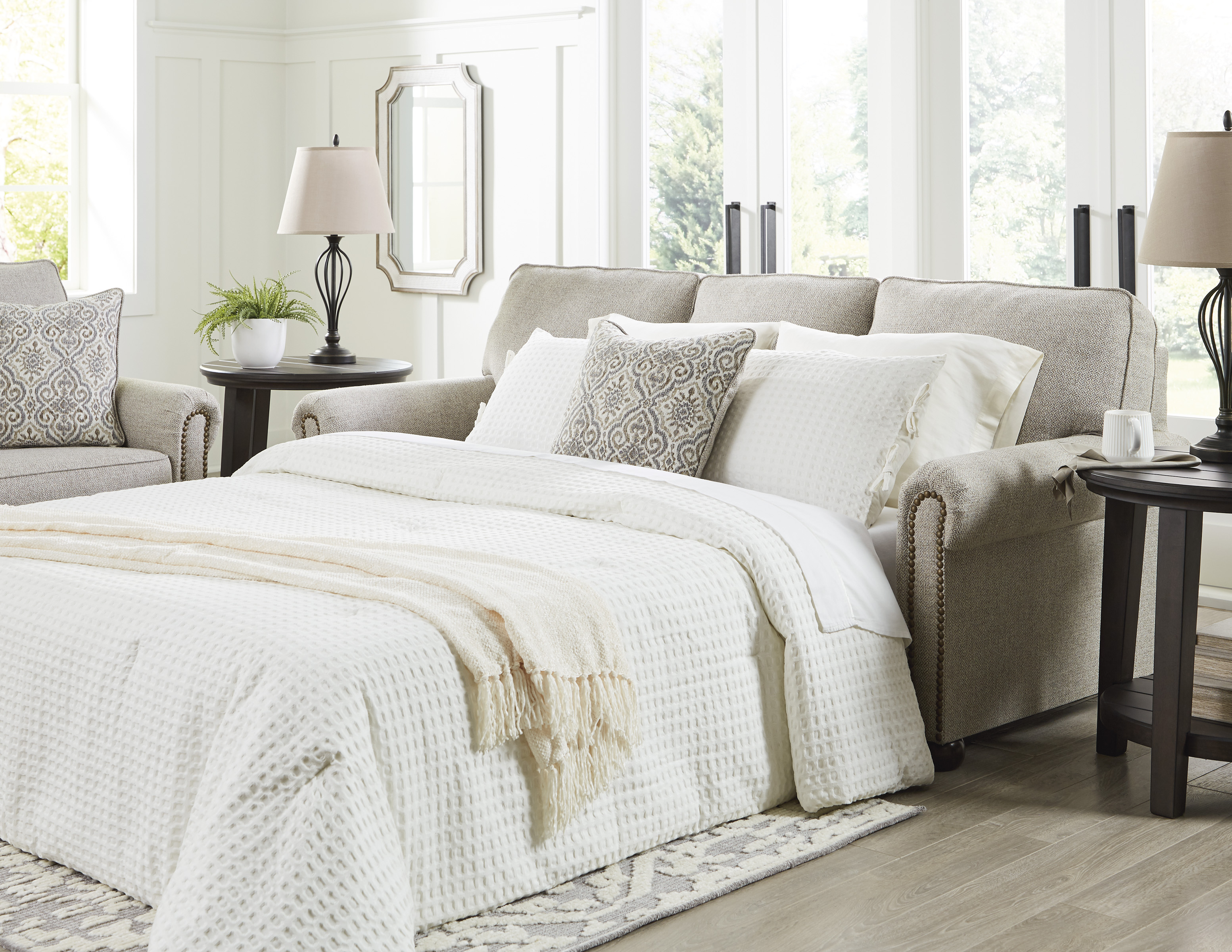 Flax colored, queen sized pull-out sofa made up for an overnight guest