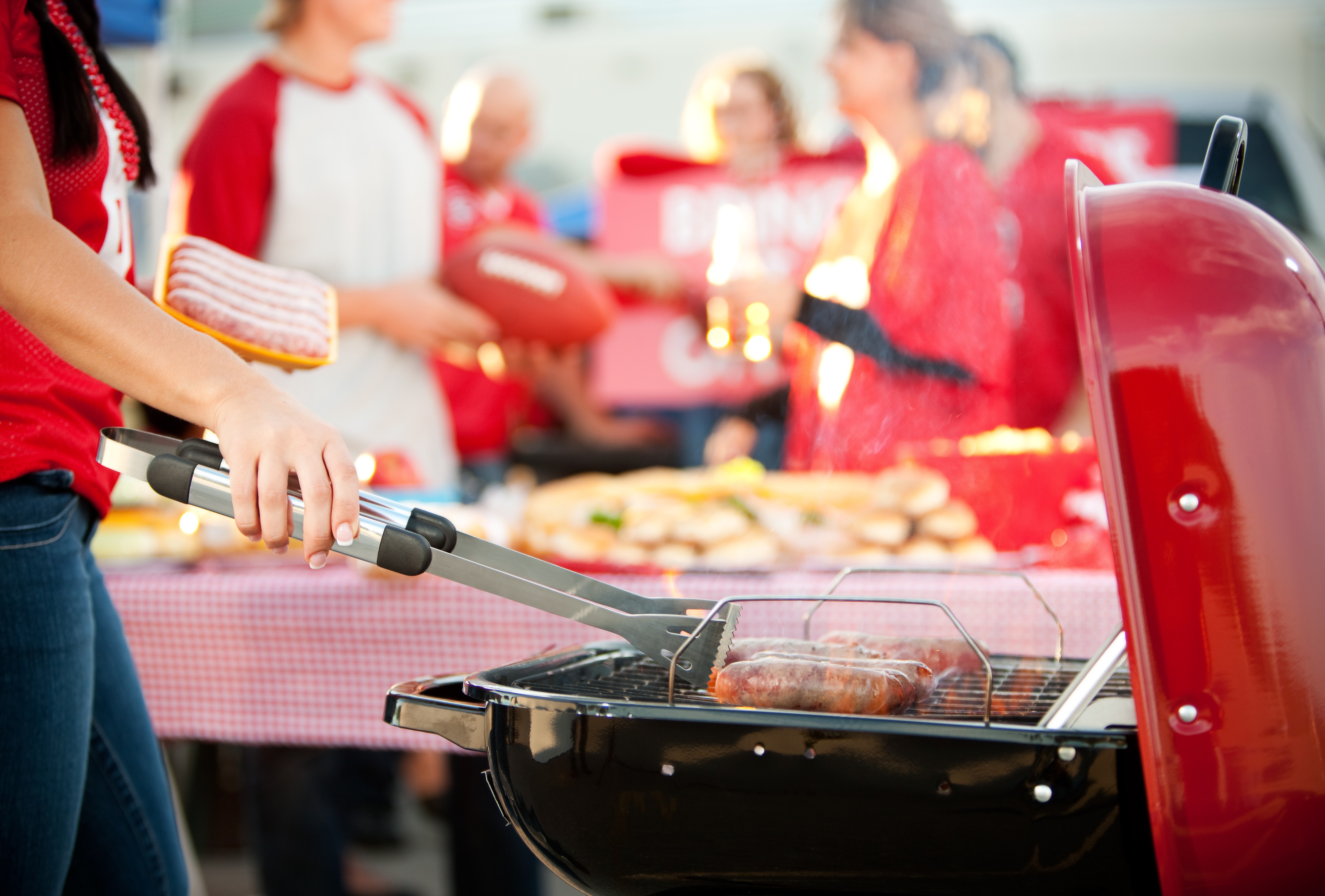 grilling for an at home tailgating party with red team colors being worn in the background
