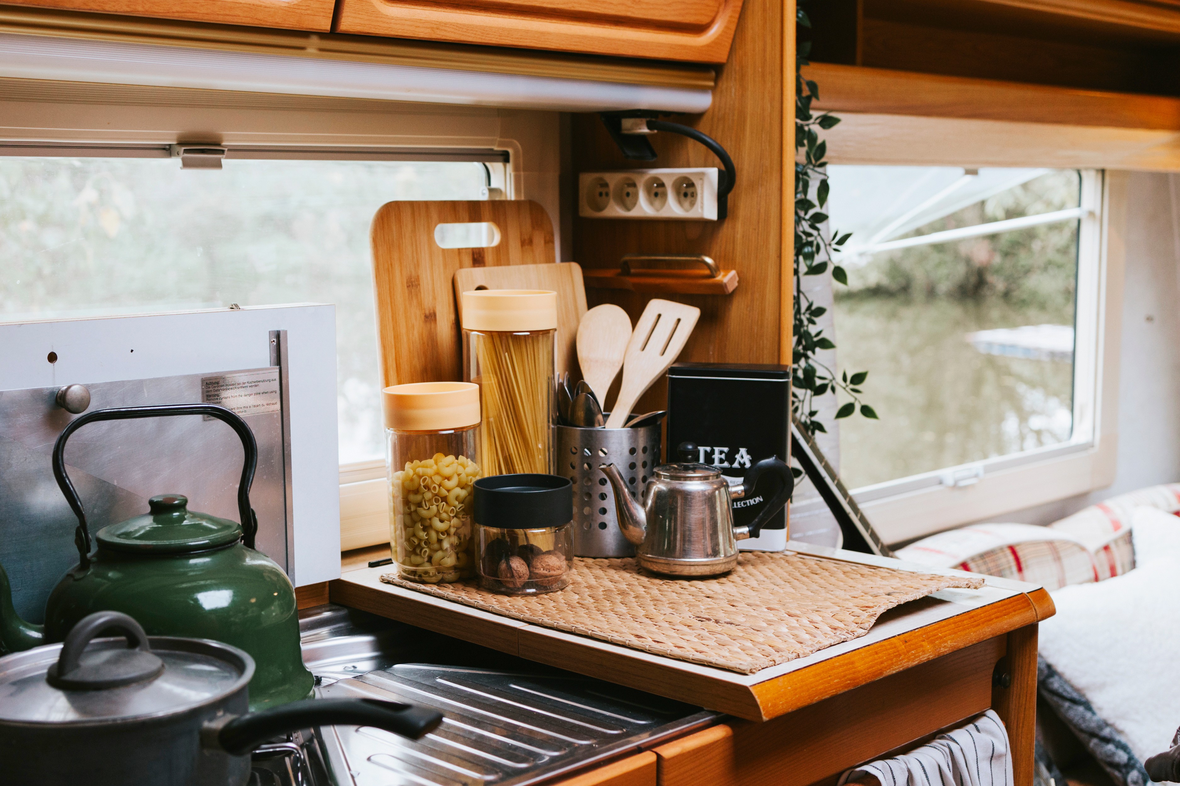 Small van kitchen with kettle on the stove looking out to a vooded view