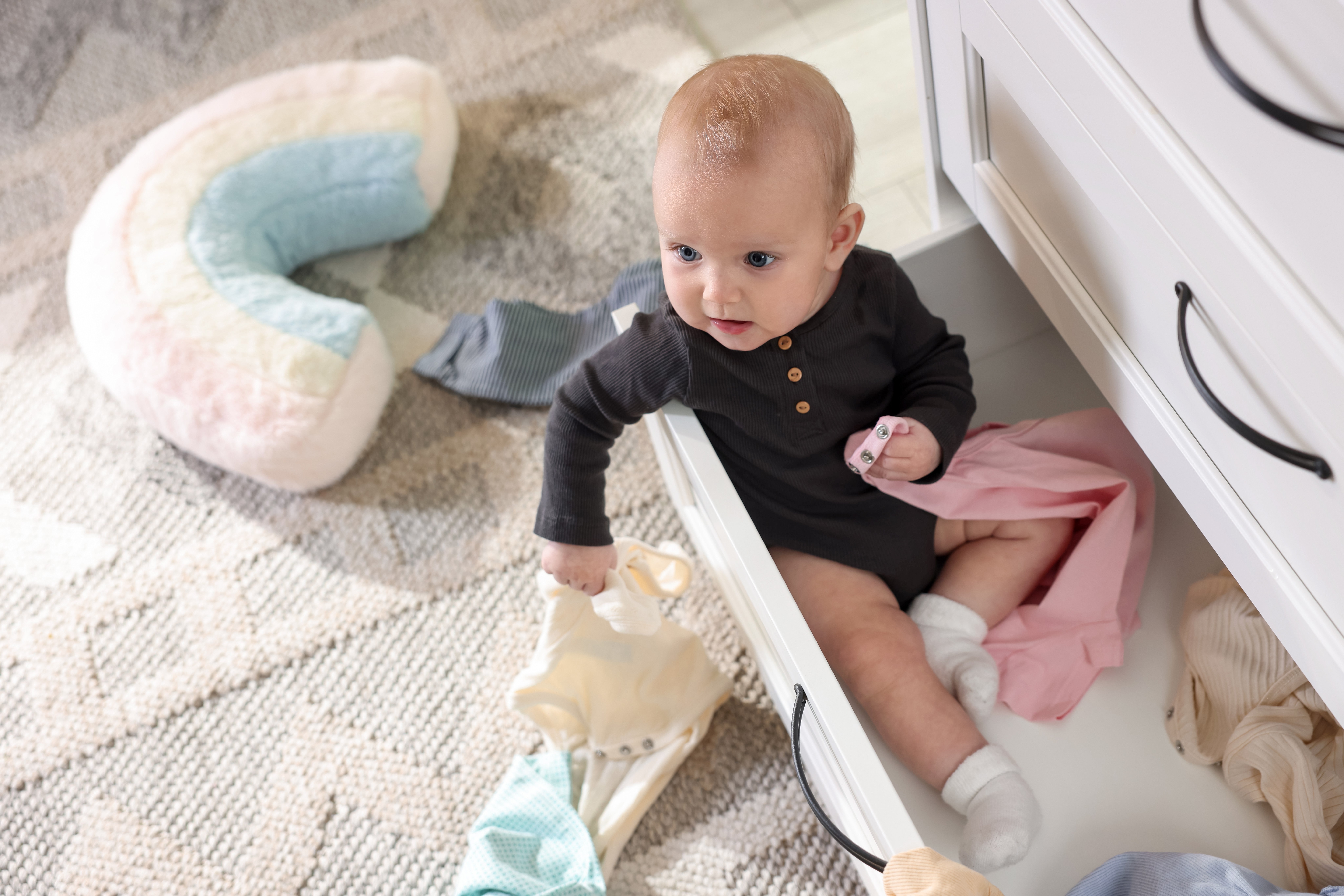 Young toddler sitting in bottom dresser drawer