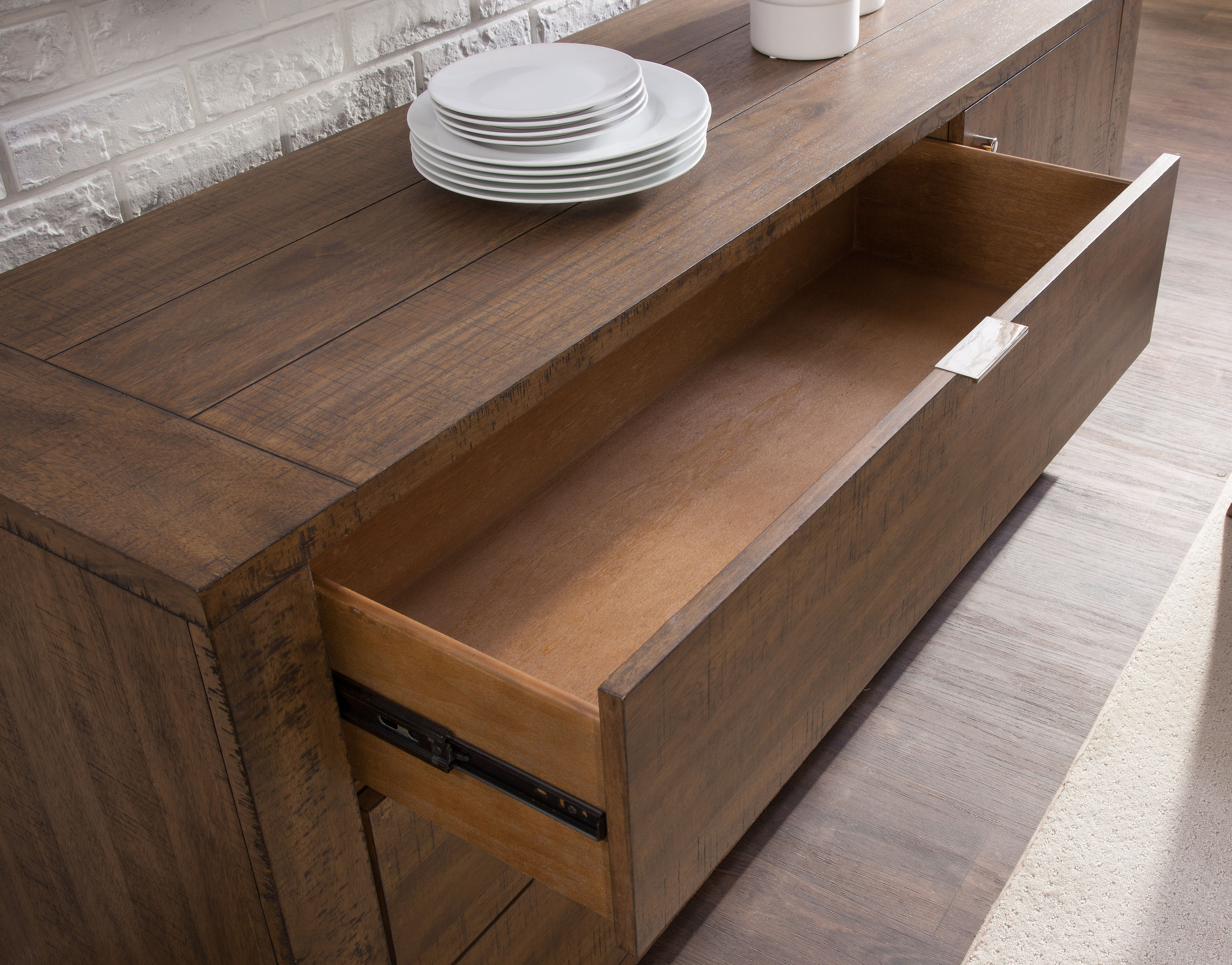 a dining room buffet with open drawer and plates on top