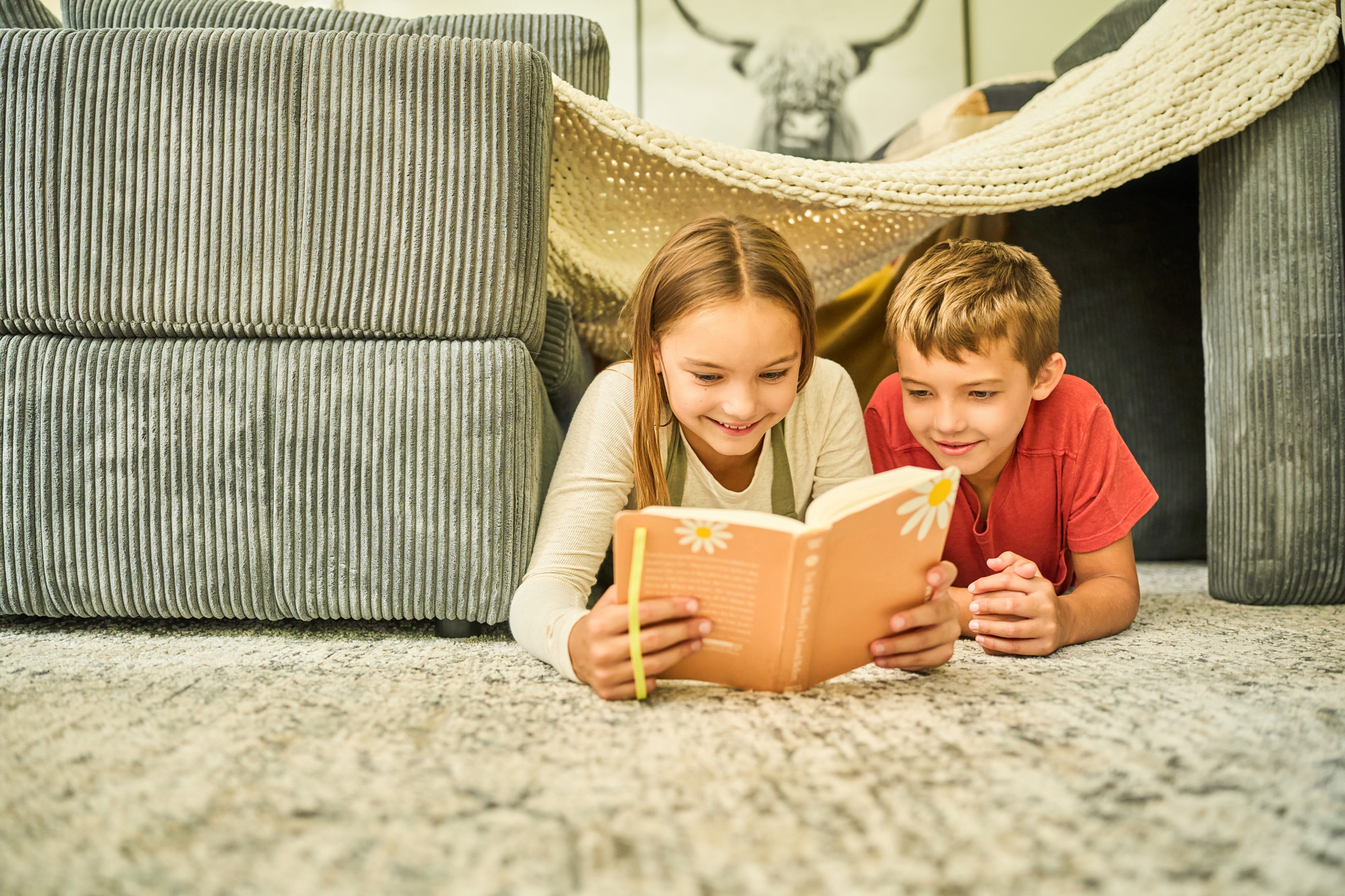 Kids reading a book next to sofa