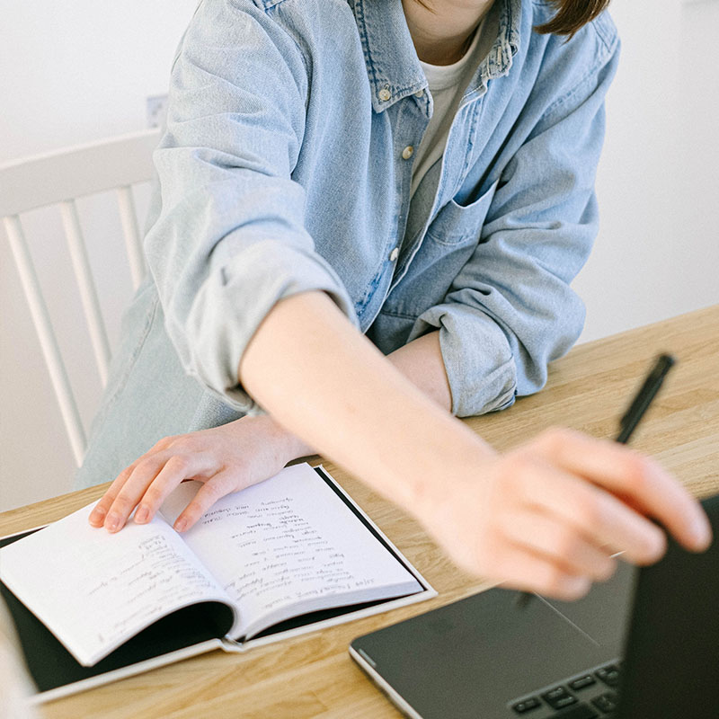 woman taking notes while using computer