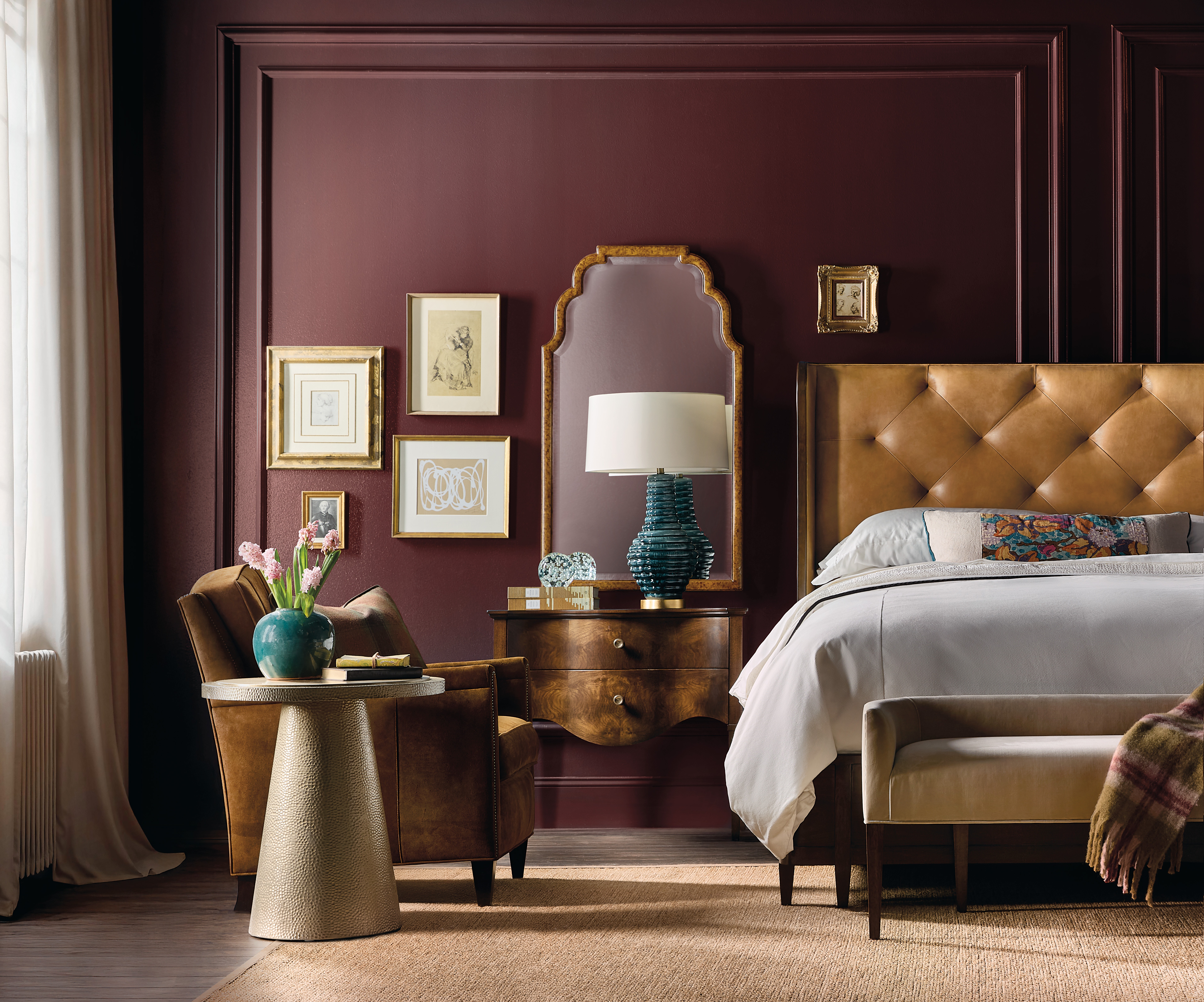 Curved leather, luxurious headboard in a dark burgndy painted bedroom