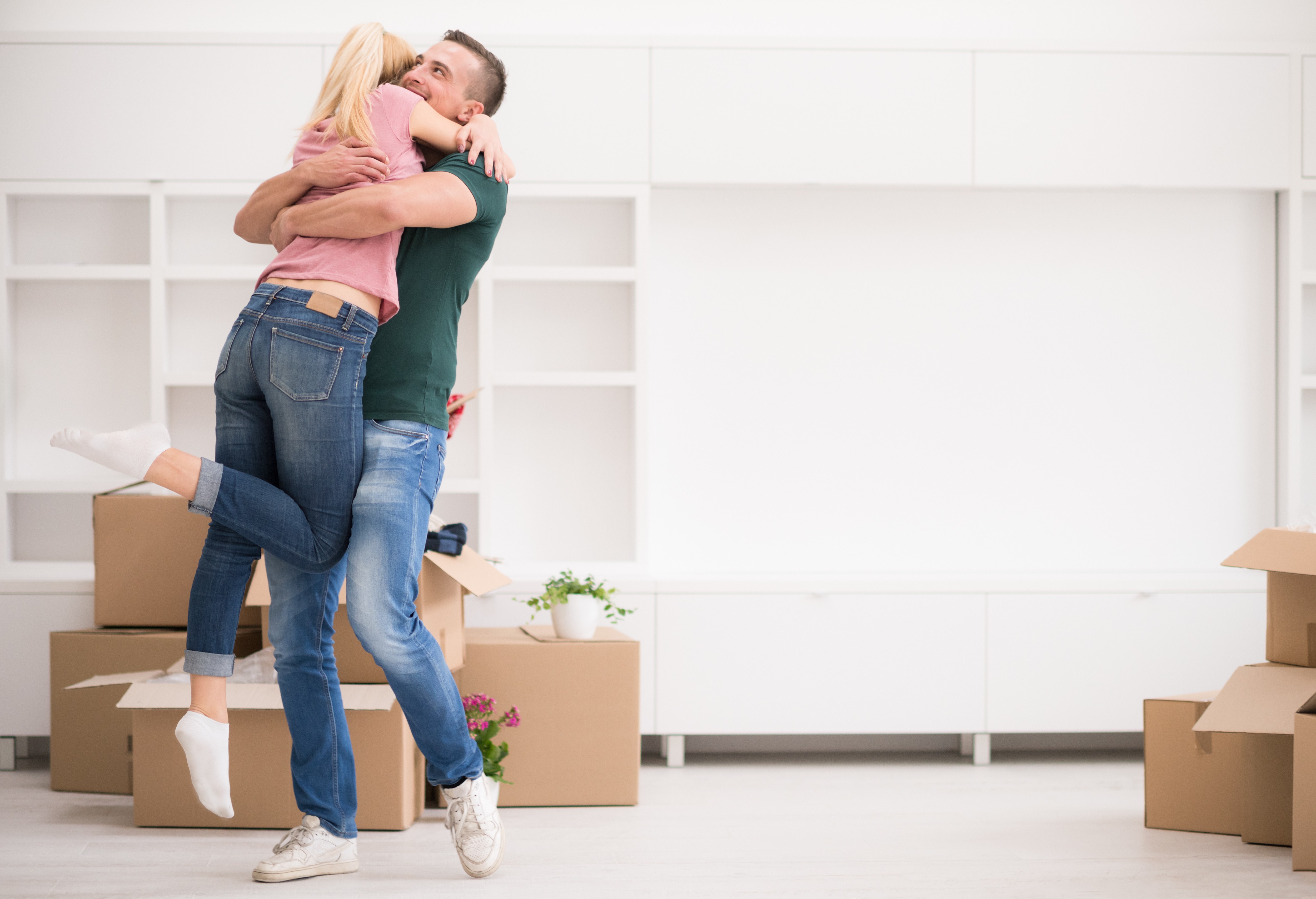 Couple with gifts in new home embracing