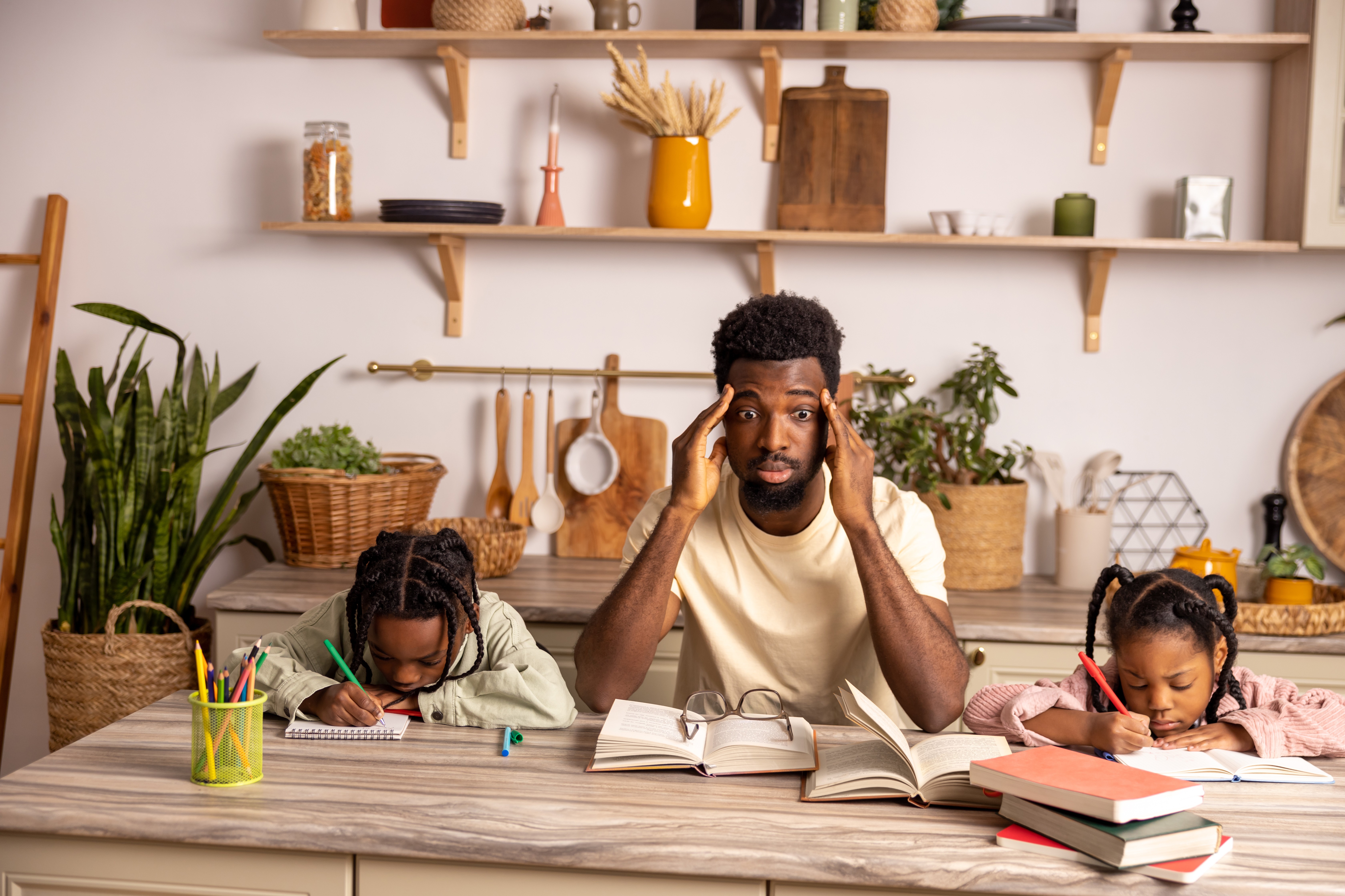 dad with two kids doing homework and dad looks overwhelmed