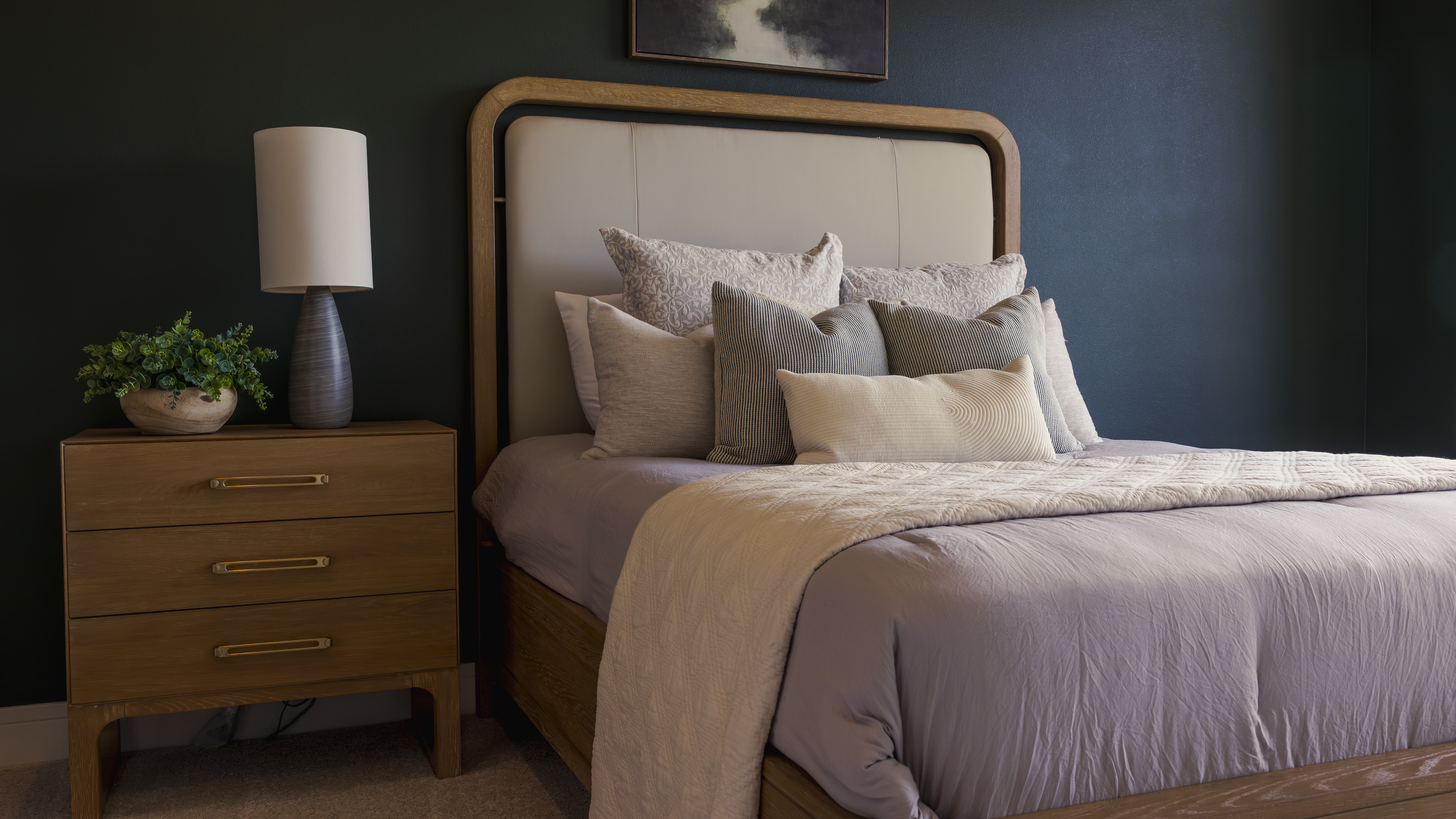 Dark moody bedroom with black accent wall and upholstered bed and light bedding