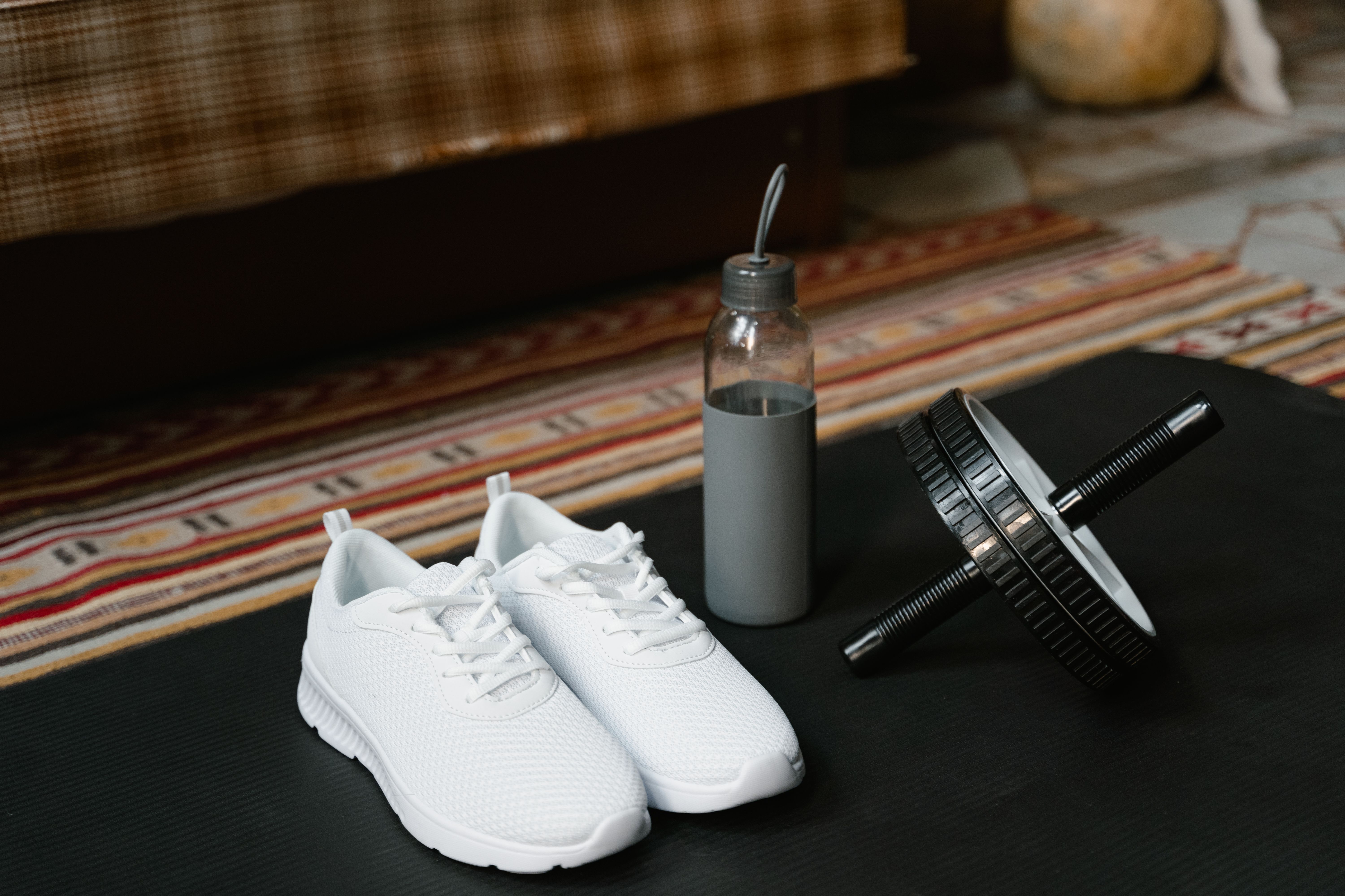 yoga mat and ab roller along side white fitness shoes